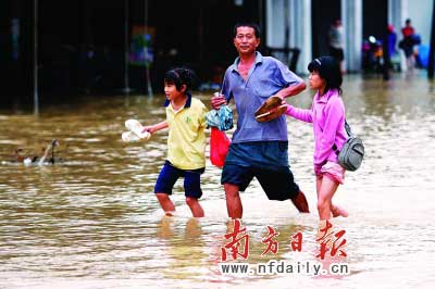 樂昌市政府前和街道被水浸,一位家長帶著孩子涉水而行。　　谷立輝童銅韶朱裕超攝