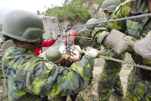 13日，臺灣高雄縣六龜鄉新開村有20多戶遭泥石流淹沒。圖為軍人正陸續將生還者救出。