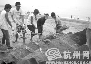 大連市金石灘國賓浴場，工作人員將帶有油污的沙子清理掉。