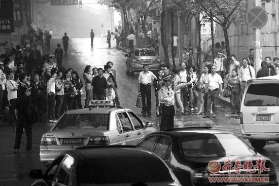  8日，在青島15中考點(diǎn)外，家長(zhǎng)排起人墻堵路，交警只能指揮途經(jīng)車輛繞行。 本報(bào)記者 楊寧 張曉鵬 攝