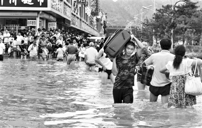 昨日，一名消防戰士在秦皇島市山海關火車站站前廣場涉水幫助旅客運送行李。 新華社發
