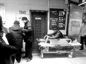 受傷工人小王坐在病床上候診。