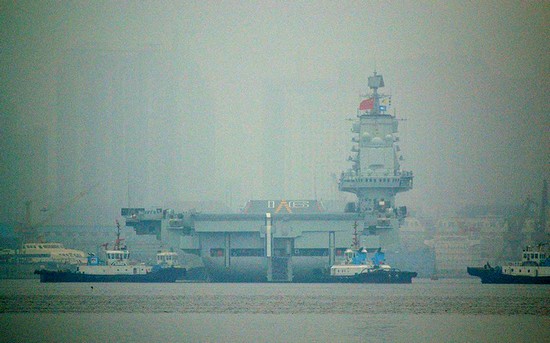 資料圖：大連港口大霧彌漫，中國(guó)首艘航母“遼寧艦”徐徐離開港口。