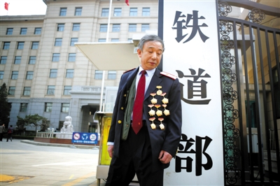 3月14日，鐵道部大門口，一位胸前掛著多枚勛章的鐵道部老職工與鐵道部牌子合影。 新京報記者 侯少卿 攝